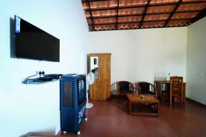 a living room with a tv and a table and chairs at Trogon resort in Kabini River