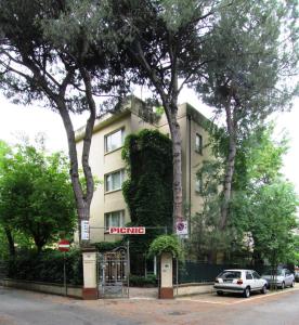 ein Gebäude mit Bäumen und Autos, die davor geparkt sind in der Unterkunft Hotel Garni Picnic in Riccione