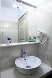 ein weißes Badezimmer mit Waschbecken und Spiegel in der Unterkunft Niriides in Lefkada Town + 58 Fotos