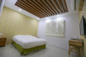 ein Schlafzimmer mit einem weißen Bett und einem Fenster in der Unterkunft Return Home B&B in Yuli