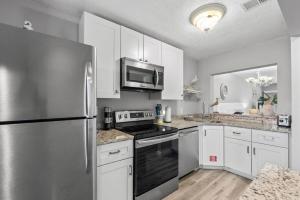 Una cocina con gabinetes blancos y un refrigerador de acero inoxidable. en Blessed by the Sea - Crescent Beach - Free Daily Activities home, en Crescent Beach