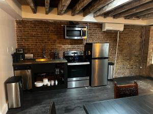 a kitchen with stainless steel appliances and a brick wall at The Perfect Apt for Large Groups Sleeps 10 in New York
