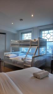 Ce lit se trouve dans un dortoir doté de 2 lits superposés et de fenêtres. dans l'établissement Leicester Soho Piccadilly For 7 VR15, à Londres