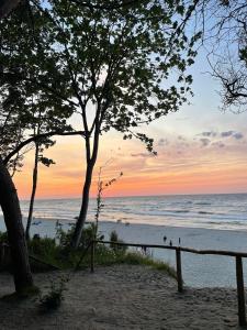 ein Sonnenuntergang am Strand mit Menschen, die am Strand spazieren gehen in der Unterkunft Natura Resort Rozewska in Jastrzębia Góra