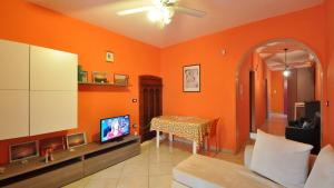 a living room with orange walls and a tv and a table at Villetta Giulia by Salento Affitti in Torre San Giovanni Ugento