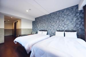 duas camas em um quarto de hotel com lençóis brancos em Montana Wing Yebisu em Osaka