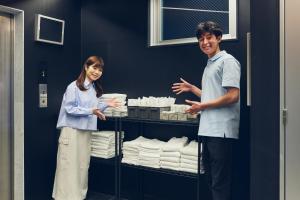 a man and a woman standing next to a rack of towels at Montana Wing Yebisu in Osaka