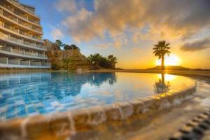a large swimming pool with a palm tree and a building at NEW Apartment with sunset views and pool in Żebbuġ