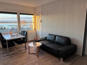 Una sala de estar con un sofá negro y una mesa. en Lee, en Fehmarn