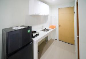 a small kitchen with a sink and a refrigerator at Best Choice and Cozy Living at 2BR at Bale Hinggil Apartment By Travelio in Medokanayu