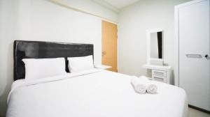 a bedroom with a white bed with two shoes on it at Best Choice and Cozy Living at 2BR at Bale Hinggil Apartment By Travelio in Medokanayu