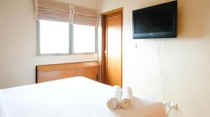 a bedroom with a bed with a tv on the wall at Extra Spacious and Homey 2BR at Kondominium Puncak Marina Apartment By Travelio in Surabaya