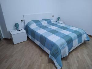 ein blau-weißes Bett in einem Zimmer mit einem Nachttisch in der Unterkunft Appartamento 2 camere 1 bagno in Voghera