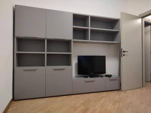 ein Wohnzimmer mit einem TV und weißen Regalen in der Unterkunft Appartamento 2 camere 1 bagno in Voghera