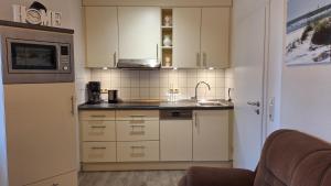 a kitchen with white cabinets and a sink and a microwave at Ferienwohnung Boje 6 in Schillig