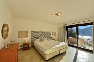 a bedroom with a bed and a large window at Villa Isola Verde in Valsolda