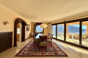 a dining room with a table and chairs and large windows at Villa Isola Verde in Valsolda