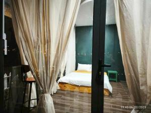 a bedroom with a bed and a window with curtains at Homestay Mẹ Khang 2 - Phòng view Sông in Cu Chi
