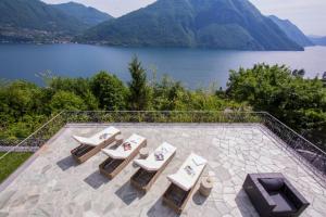 a patio with chairs and a view of a lake at Villa Isola Verde in Valsolda