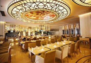 a restaurant with tables and chairs and a large chandelier at Jinjiang Fuyuan Hotel in Daxing