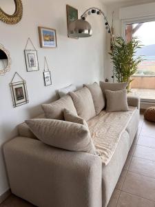 a couch sitting in a living room with a window at Appartement avec vue panoramique sur le Golf de Propriano in Propriano +13 photos