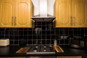 a kitchen with wooden cabinets and a stove top oven at Spacious 4 Bed with Free Parking in Southampton +29 photos