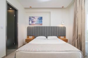 a bedroom with a large bed with a gray headboard at Aegean Sun Hotel in Skala Rachoniou