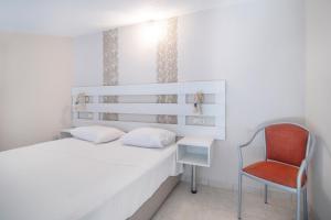 a bedroom with a white bed and a red chair at Aegean Sun Hotel in Skala Rachoniou