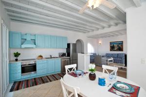 a kitchen with blue cabinets and a table and chairs at Sofia's Bungalows Mykonos in Mikonos