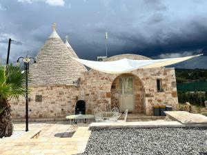 a stone building with a white canopy over a patio at Trulli San Pietro in Putignano