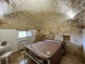 a bedroom with a bed with a brick wall at Trulli San Pietro in Putignano