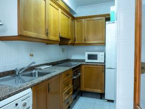 a kitchen with wooden cabinets and a white refrigerator at Apartamento Pinzón in Moncófar +6 photos
