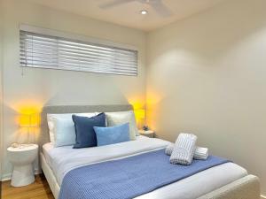 a bedroom with a bed with blue and white pillows at Merewether By The Beaches Newcastle, Free Parking, Ocean View in Newcastle