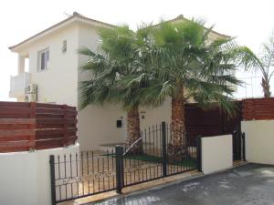 einen Zaun mit zwei Palmen vor einem Haus in der Unterkunft Athena Villa in Ayia Napa