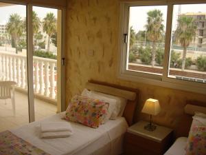 a bedroom with a bed and a balcony with palm trees at Athena Villa in Ayia Napa +58 photos