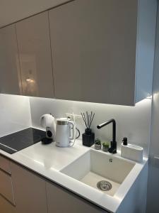 a white kitchen with a sink and a counter at Palanga Suites in Palanga