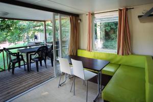 a dining room with a green couch and a table and chairs at Camping de la Base Nautique in Saint-Rome-de-Tarn +26 photos
