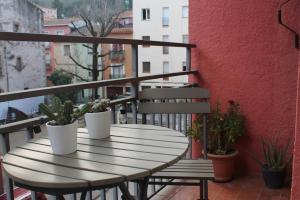 a wooden table on a balcony with potted plants at Apto el Piset, acogedor y céntrico del Montseny in Arbúcies