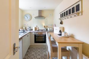 a kitchen with a table and a clock on the wall at Acorn Cottage in Quorndon