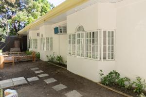 a white building with windows and a wooden bench at Baroro Beach House LU in Bacnotan