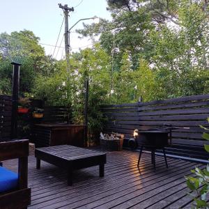a wooden deck with a bench and a grill at Del Bosque Surf Ranch in Villa Gesell