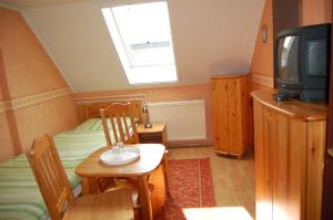a small room with a bed and a table and a tv at Czérna Vendégház in Tata