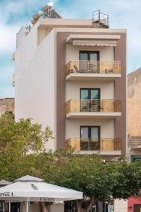 a tall white building with a balcony and an umbrella at Dimi Studio Image in Ierápetra