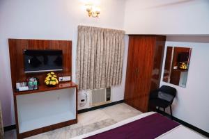a hotel room with a bed and a television at Rich inn Palace Tnagar in Chennai