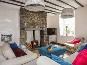ein Wohnzimmer mit Couch und Kamin in der Unterkunft Riverwash Cottage in Penmaen-mawr