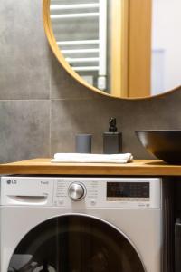 a mirror above a washing machine in a bathroom at BudaVibe Apartman w AC by NW in Budapest