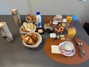 a table with a breakfast of bread and orange juice at Chez Stéphanie et Sylvain in Le Mesnil-Villeman