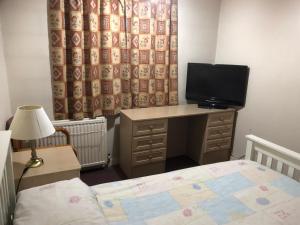a bedroom with a bed and a desk with a television at SJGUESTHOUSE LONDON Single Room A in London
