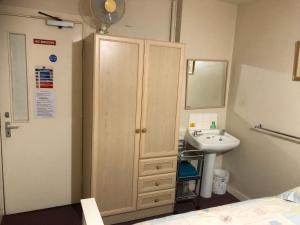 a bathroom with a sink and a wooden cabinet at SJGUESTHOUSE LONDON Single Room A in London