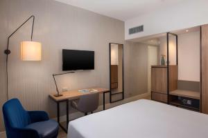 a hotel room with a bed and a desk and a tv at NH Trieste in Trieste